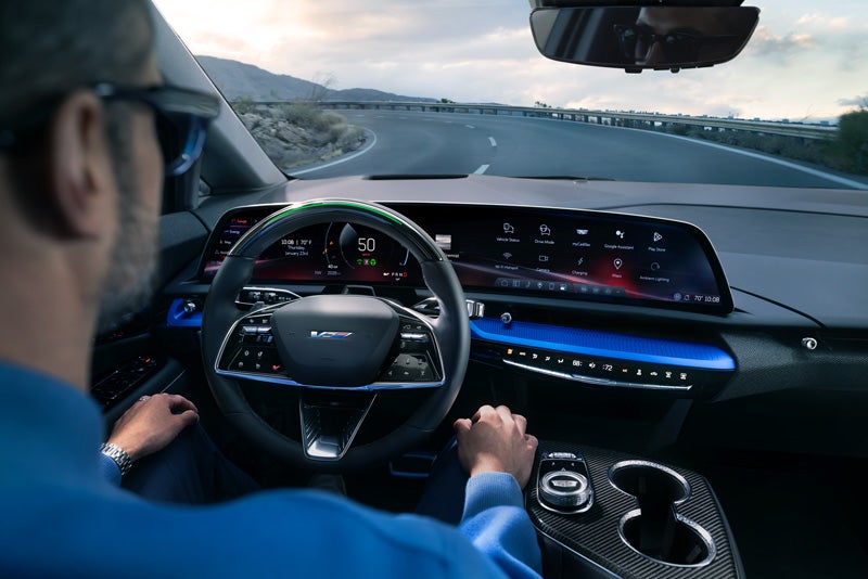Front View of the 2026 OPTIQ-V Driving Through the Dusk Utilizing its Headlights | Holloway Cadillac in PORTSMOUTH NH